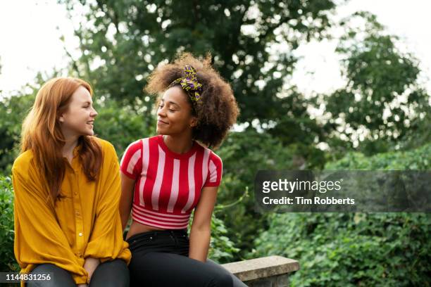 two women sat on wall - discussion foto e immagini stock