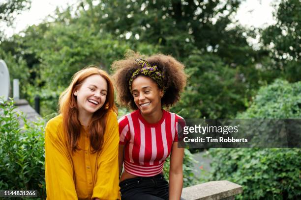 two women laughing together - garden talking photos et images de collection