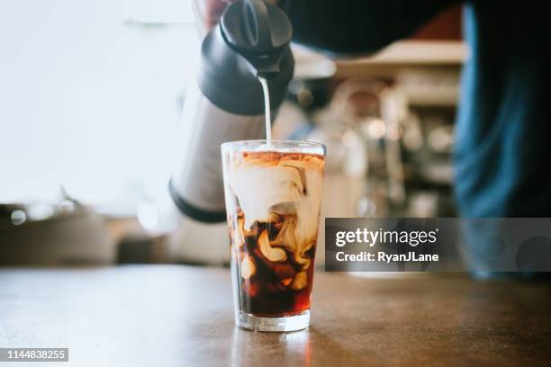 barista pours milk into cold brew coffee - coffee and milk stock pictures, royalty-free photos & images