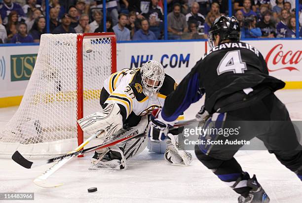 Tim Thomas of the Boston Bruins reaches to push the puck away from Vincent Lecavalier of the Tampa Bay Lightning during the third period in Game Four...