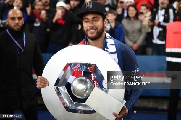 Paris Saint-Germain's Brazilian forward Neymar celebrates with the champion's trophy at the end of the French L1 football match between Paris...