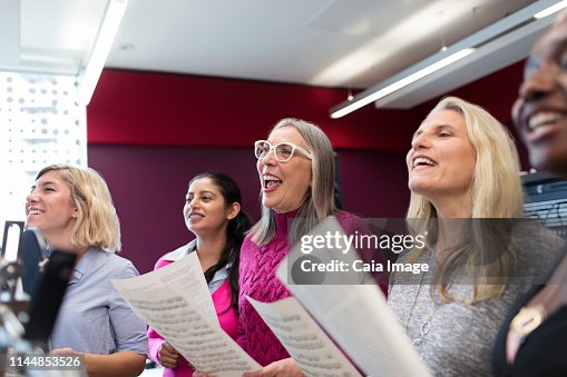 Womens choir with sheet music singing in music recording studio Womens choir with sheet music singing in music recording studio