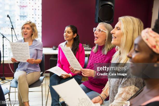 womens choir with sheet music singing in music recording studio - choir uk stock pictures, royalty-free photos & images