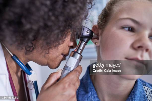 close up female pediatrician using otoscope, examining ear of girl patient - ear close up women stock-fotos und bilder