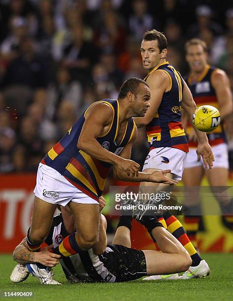 Graham Johncock of the Crows handballs whilst being tackled by Dayne Beams of the Magpies during the round nine AFL match between the Collingwood...