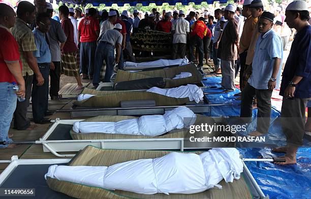 Body of landslide victims lie on the ground during a funeral in Hulu Langat, Selangor on May 22, 2011. A close-knit village on the outskirts of the...