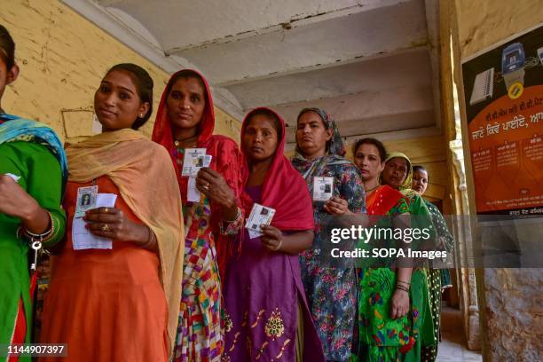 Indian women seen showing their identity cards as they queue to cast their vote at a polling station during the final phase of India's general...