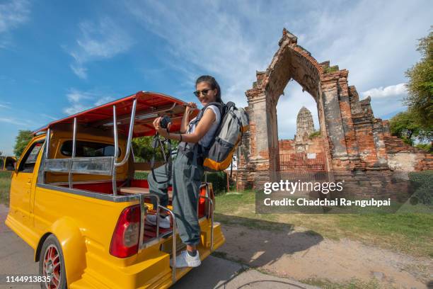 travel concept.tourist happy are traveling.tourist holding camera stand in tuk tuk thai traditional taxi with blurring old town ayutthaya background. - rickshaw or tuk tuk or surrey or pedicab stock pictures, royalty-free photos & images