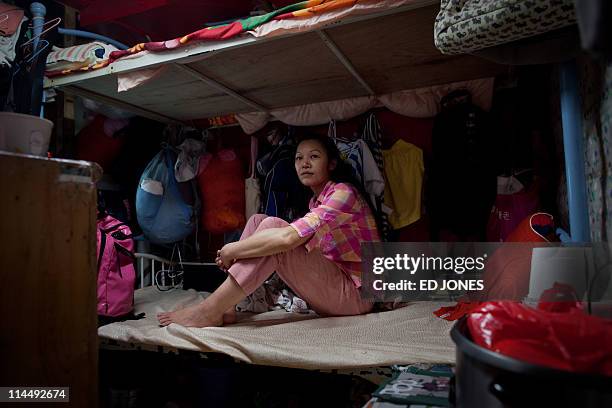 Cubicle home resident surname Lau sits in the room she shares with two other family members, in Hong Kong on May 20, 2011. Amid rising inflation many...
