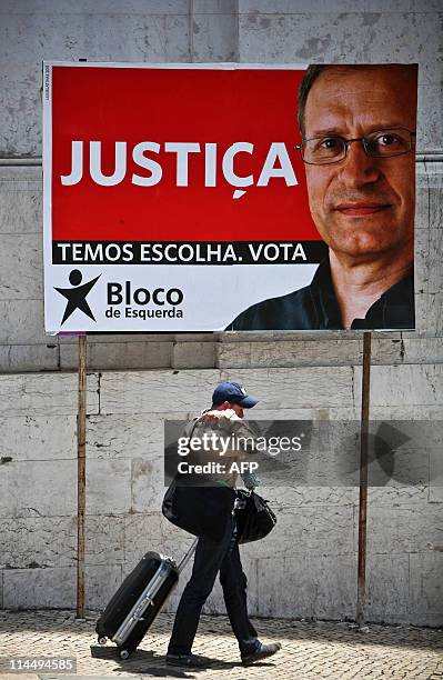 Man walks past an election campaign billboard featuring leader of the Bloco de Esquerda, Francisco Louca ahead of the upcoming general elections in...