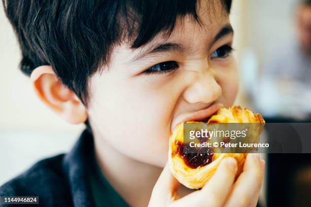 boy eating pastel de nata - vanillesoße stock-fotos und bilder