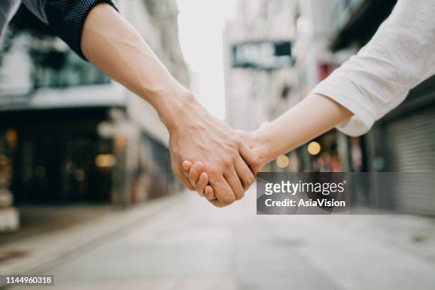nahaufnahme von ehepaar hält hände gegen stadtstraßen-szene - holding hands close up stock-fotos und bilder