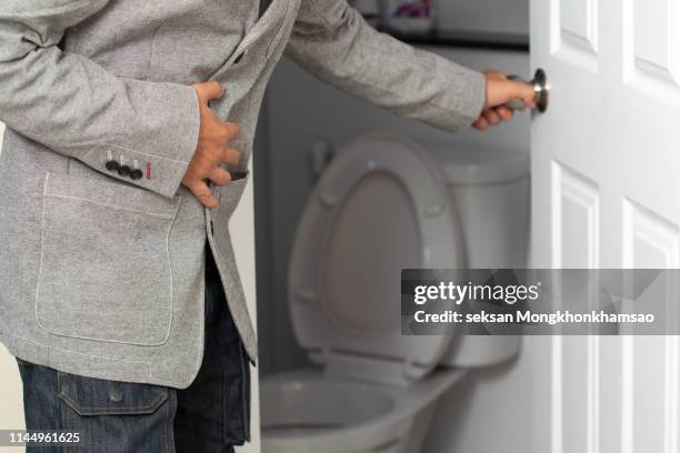 side view of man suffering from stomachache sitting on toilet seat - diarrhoea foto e immagini stock