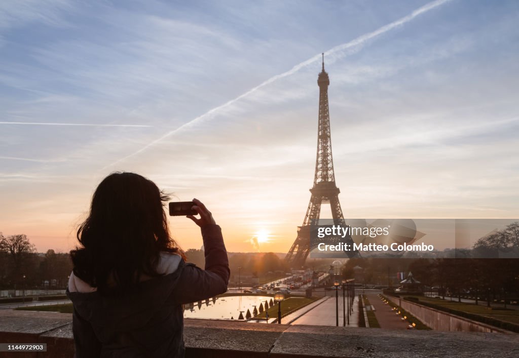 Woman taking a photo of the Eiffel tower, Paris, France
