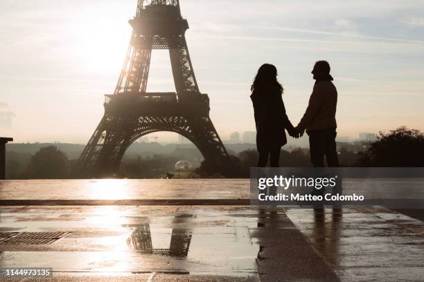 couple holding hands at the eiffel tower, paris - couple paris tour eiffel trocadero stock-fotos und bilder