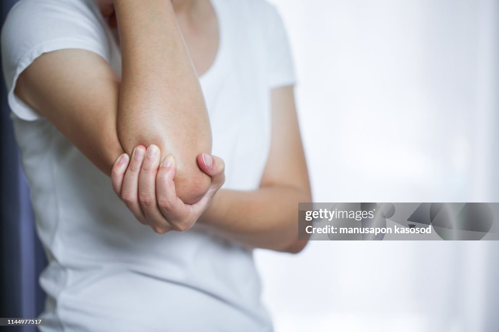 Close up woman's hand holding her elbow . Elbow pain concept.