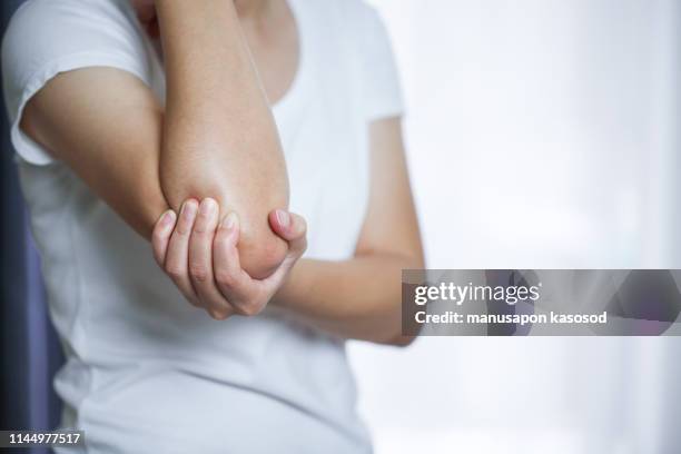 close up woman's hand holding her elbow . elbow pain concept. - pain stockfoto's en -beelden