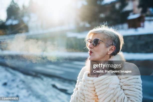 a portrait of an active senior woman standing outdoors in winter, breathing out. copy space. - nice old town stock pictures, royalty-free photos & images