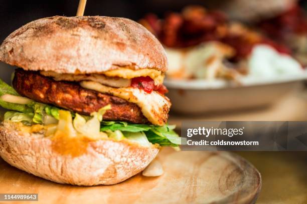 frisch gegrillte vegetarische halloumi cheeseburger auf holztheke auf lebensmittelmarkt - fleischersatz stock-fotos und bilder