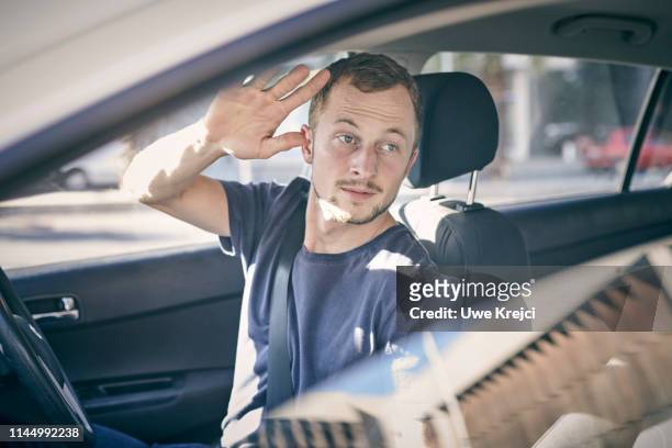 young man in car - sventolare la mano foto e immagini stock
