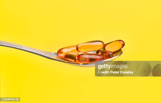 cod liver oil capsules on spoon - vitamin d stockfoto's en -beelden