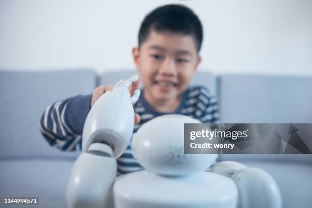 smart boy berührt roboter-finger im innenbereich - kids modern school life stock-fotos und bilder