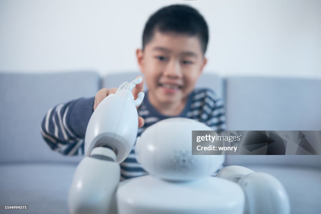 Smart boy touching robot finger indoors