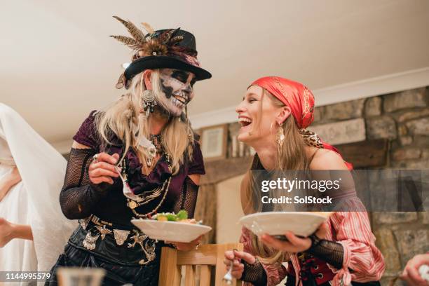 vrienden lachen en eten - adult halloween party stockfoto's en -beelden