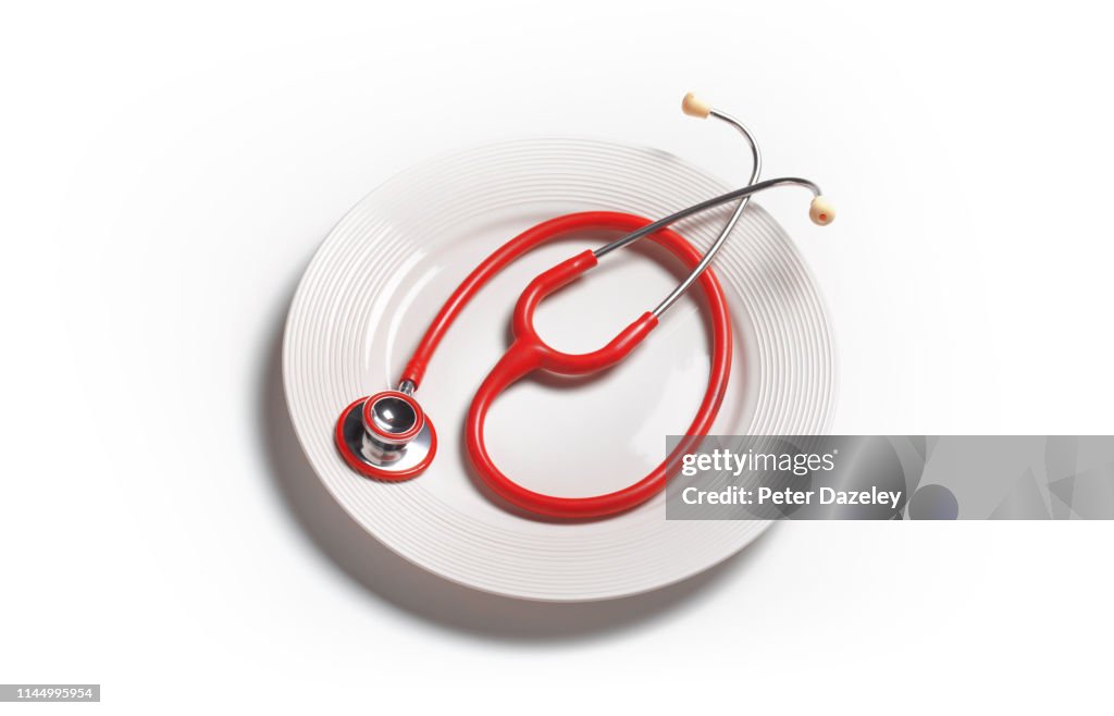 Red stethoscope on white plate