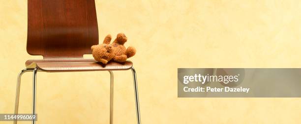 teddy bear left abandoned on chair - child abuse stock-fotos und bilder