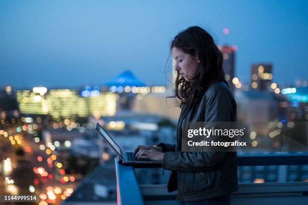 若い女性は、彼女のラップトップでタイピング、バックグラウンドでベルリンの街並みを照らし、トワイライト - berlin people ストックフォトと画像