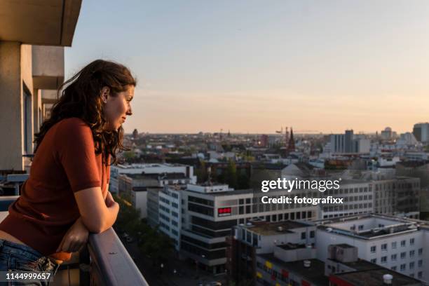 porträtt av ung kvinna lutar på balkongen och ser över berlins skyline medan solnedgången - balkong bildbanksfoton och bilder