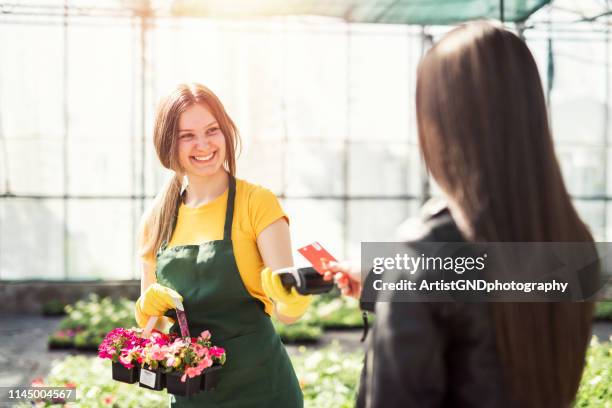 greenhausarbeiter verkaufen topfblumen. kontaktlose kartenzahlung. - kartenspiel stock-fotos und bilder