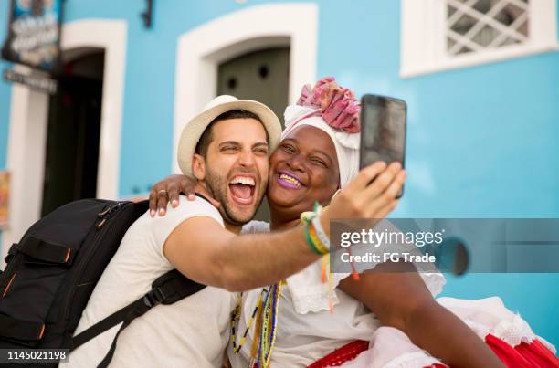 tourist taking a selfie with baiana (traditional brazilian woman) in bahia, brazil - salvador bahia stock pictures, royalty-free photos & images