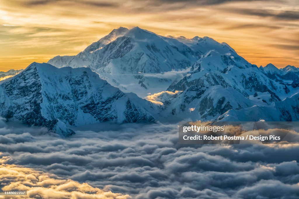 Aerial image of the Saint Elias mountains in Kluane National Park and Reserve. This is Mount Logan, Canada's highest peak rises above the storm clouds below as sunset lights up the clouds above