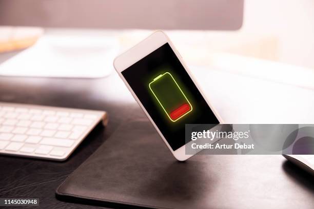 mobile phone without battery levitating in office desk. - battery low stock-fotos und bilder