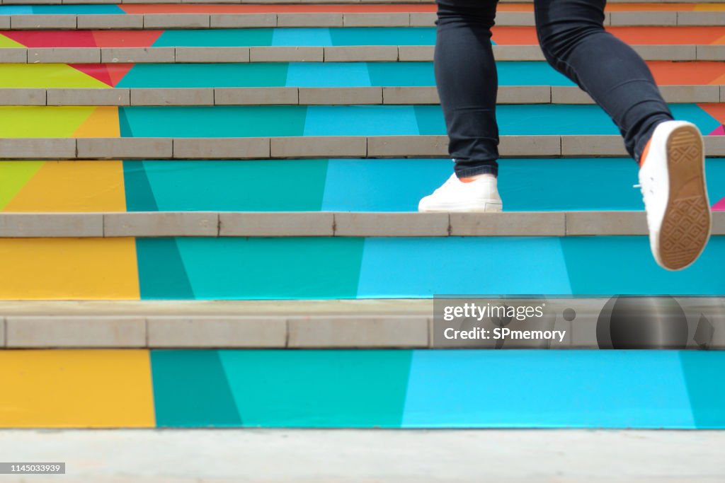 Lower part of teenage girl in casual shoe walking up outdoor colorful stair,teenage lifestyle successful concept