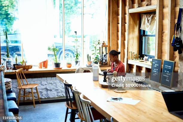 woman using laptop at wooden dining table - hythe stock-fotos und bilder