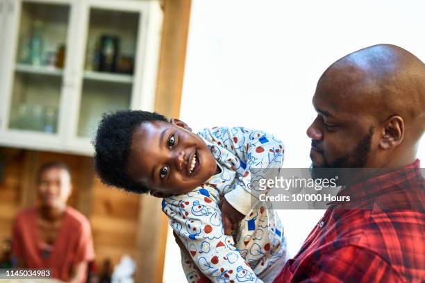 portrait of father holding cheerful boy with cute face - red shirt stock pictures, royalty-free photos & images