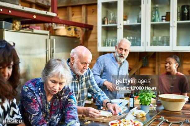 seniors preparing fresh food on kitchen counter for friends - hythe stock-fotos und bilder