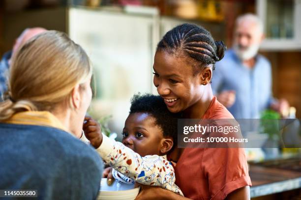 cheerful mother watching son touch friend and smiling - nephew stock pictures, royalty-free photos & images