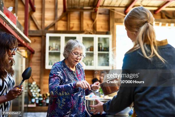 senior woman wearing glasses and holding saucepan - ritratto nonna cucina foto e immagini stock