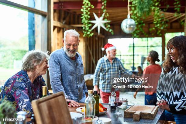 senior man smiling and laughing with friends at christmas gathering - christmas elderly stock pictures, royalty-free photos & images