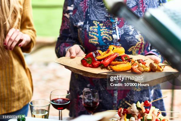 woman holding wooden platter with char grilled vegetables - mediterranean food stock pictures, royalty-free photos & images