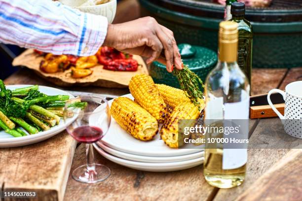 plate of freshly barbecued corn on the cob and herbs - summer grilling stock pictures, royalty-free photos & images