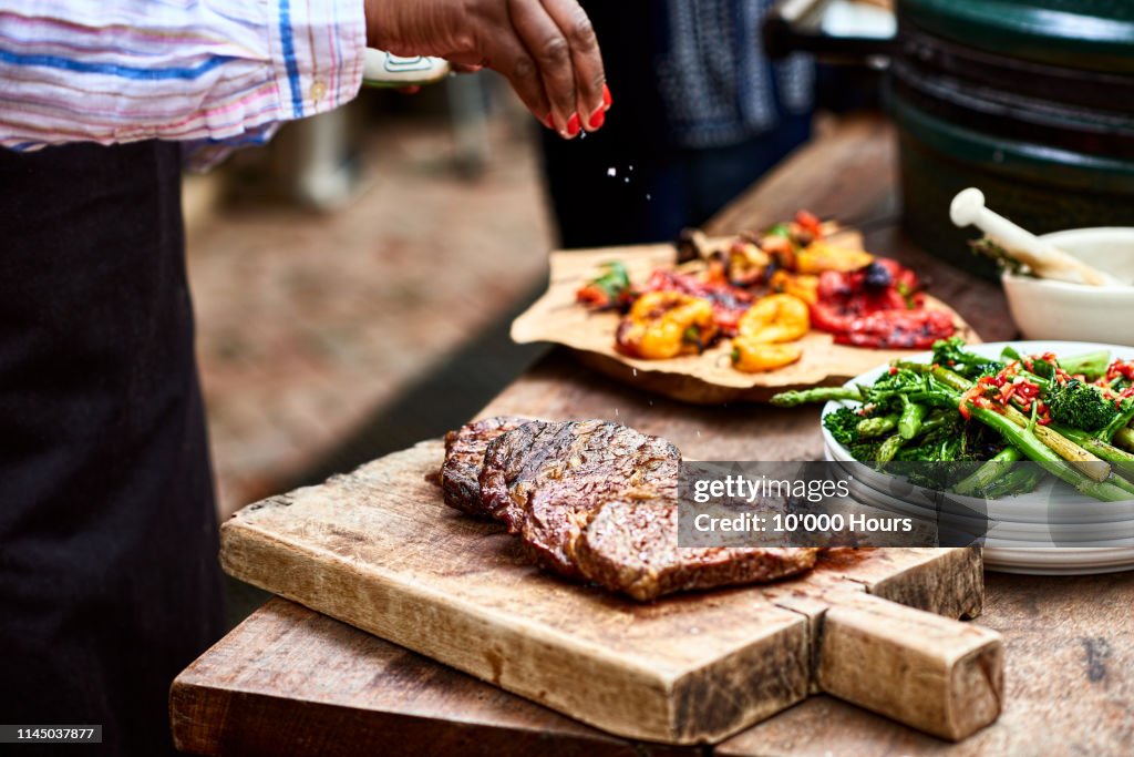 Woman sprinkling salt on freshly cooked steak