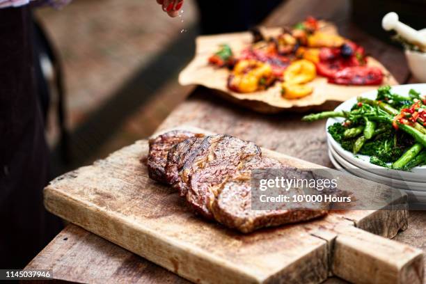 freshly cooked steak on wooden board with salt flakes - summer grilling stock pictures, royalty-free photos & images