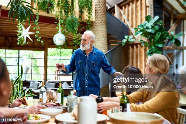mature man making speech at dinner table with friends - hythe stock-fotos und bilder