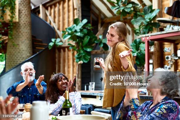 cheerful woman making speech at party smiling and shrugging - family moments ストックフォトと画像