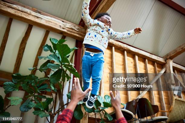 excited young boy mid air above dad's head with arms out - dad throwing kid in air stockfoto's en -beelden